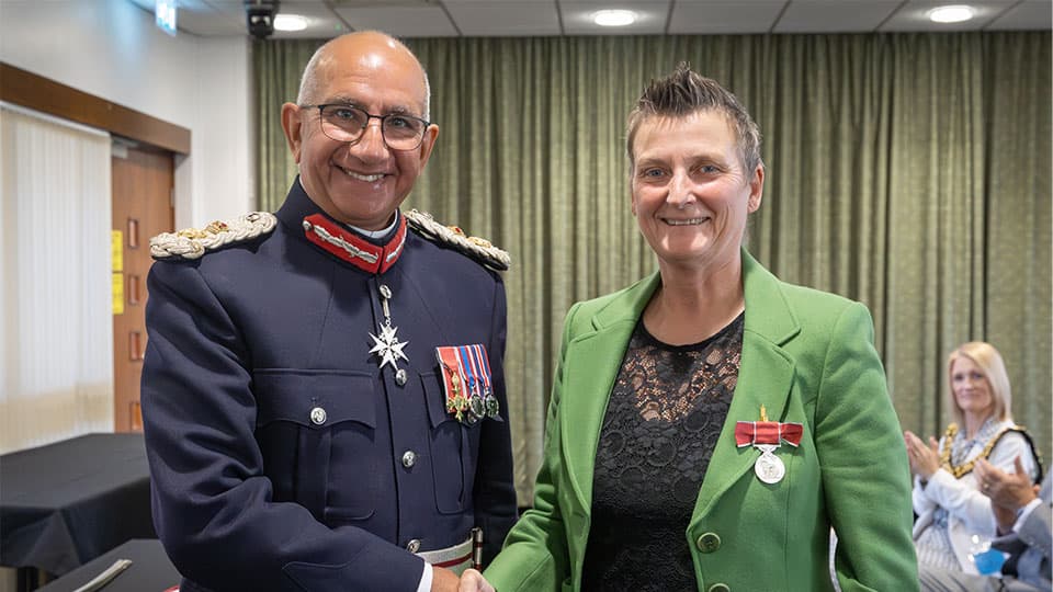 Monday 29th September at County Hall, Glenfield where the Lord-Lieutenant of Leicestershire, Mike Kapur OBE CStJ presented Karen Setchell with the British Empire Medal. They are shaking hands and smiling.